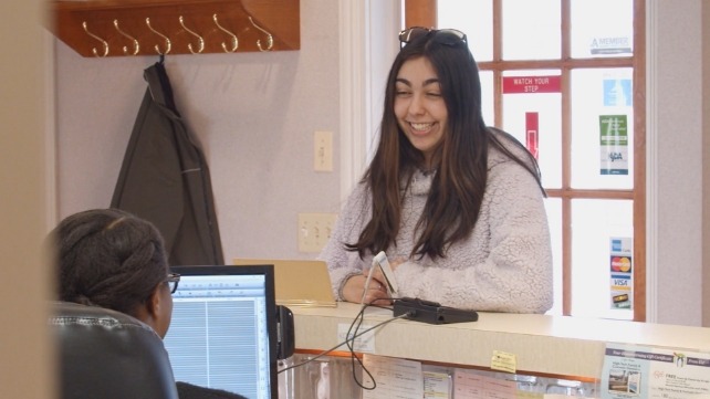 Patient smiling at dental team member behind reception desk