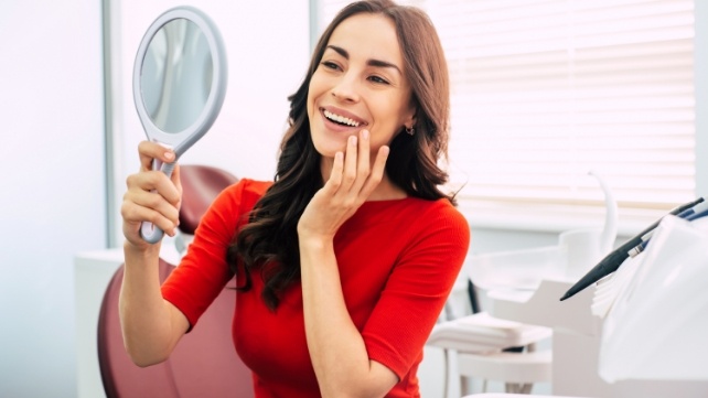 Woman looking at smile after cosmetic dentistry with smile vision technology