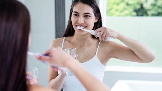 Woman brushing teeth to prevent dental emergencies