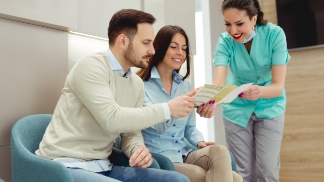 Dental team member and patients reviewing dental insurance information