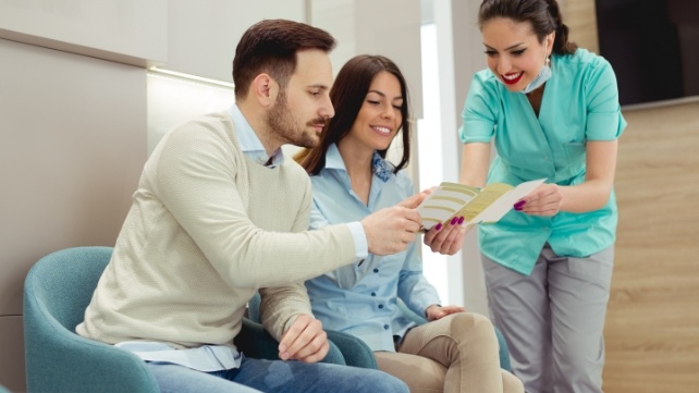 Dental team member and patients reviewing dental insurance information